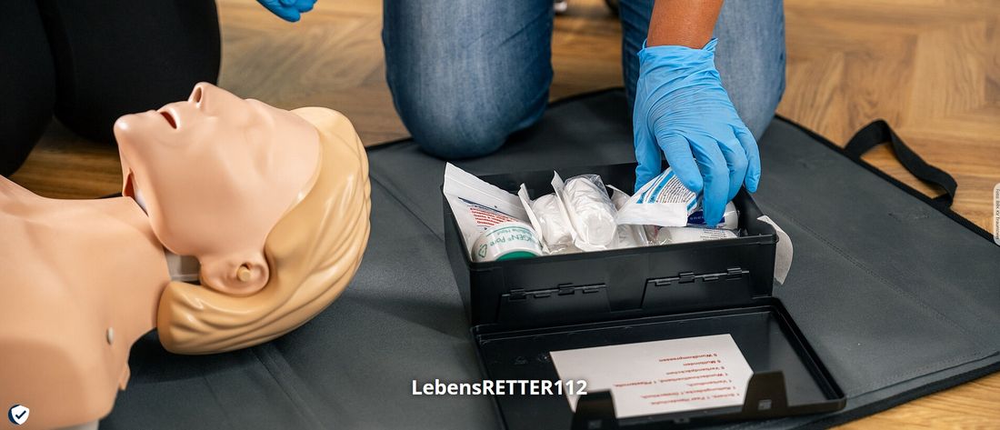 Erste-Hilfe Puppe liegt am Boden mit Utensilien des BRK
